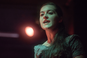A white woman in gray dress looking severe.