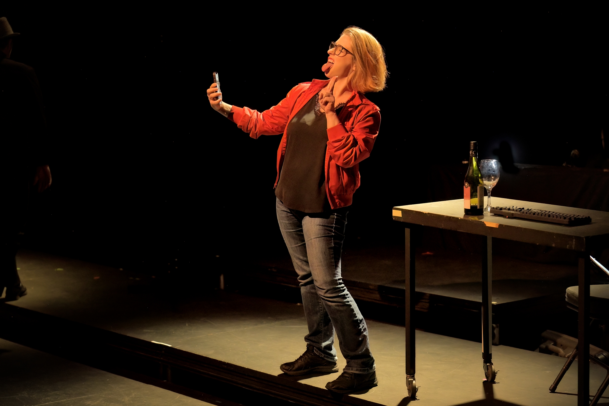 A white woman in a red jacket takes a selfie, sticking out her tongue.